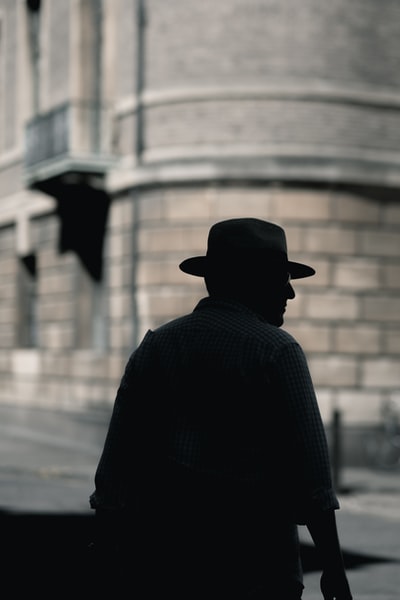 轮廓与帽子站在一个男人的照片在白天的混凝土建筑
